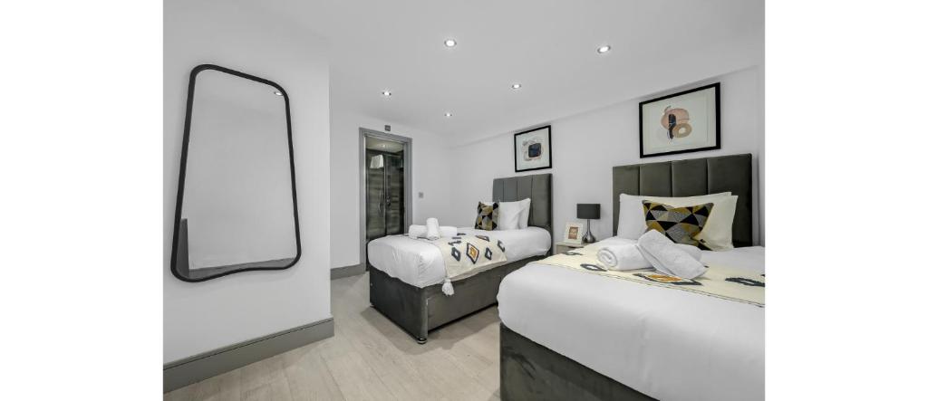 - une chambre avec 2 lits et un miroir dans l'établissement Easy Two Bedroom Flat in Hipster Hackney, à Londres