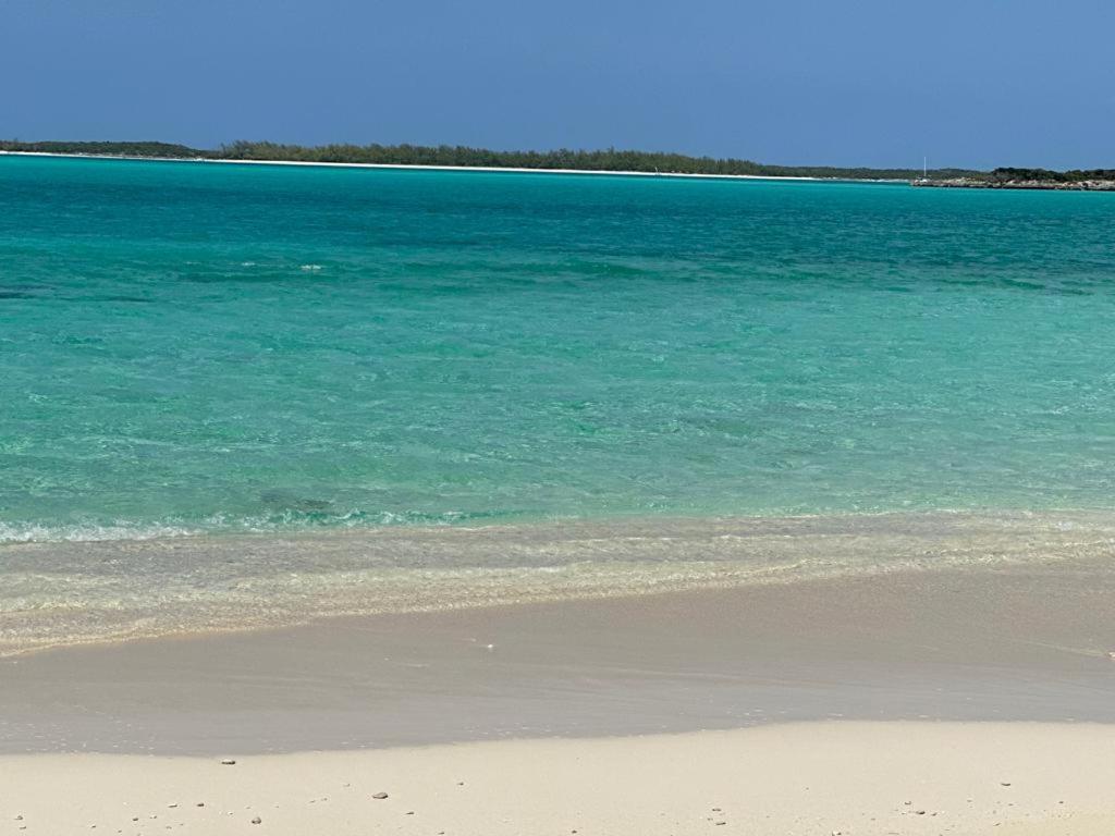 uma praia com a água azul e areia em Sheer Bliss BeachView Apt #4 em Exuma Harbour Estates