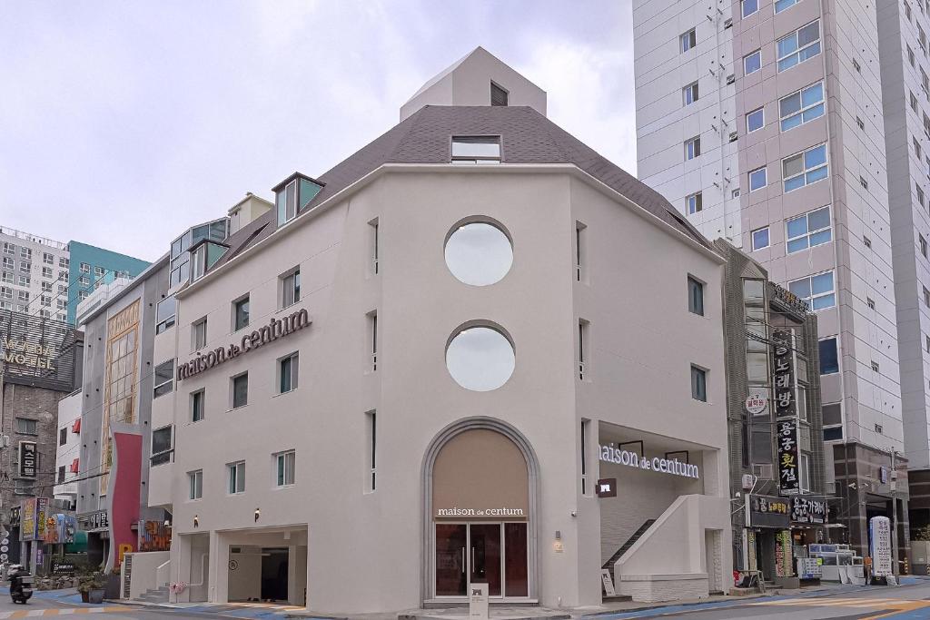 a white building with a round window on a city street at Maison de Centum Busan in Busan