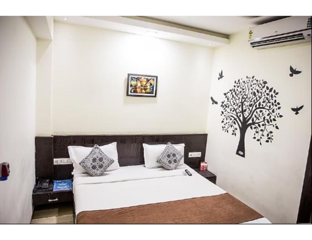 a bedroom with a bed with a tree on the wall at Hotel Wardhman, Jabalpur in Jabalpur
