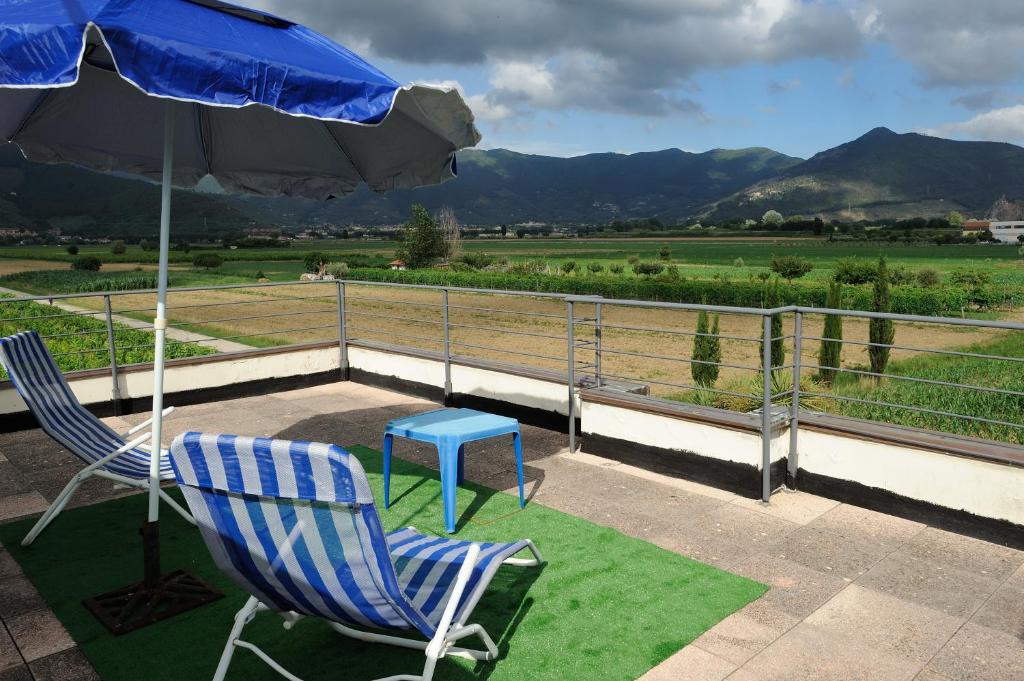 - une terrasse avec 2 chaises, un parasol et une table dans l'établissement Villa La Certosa, à Pise