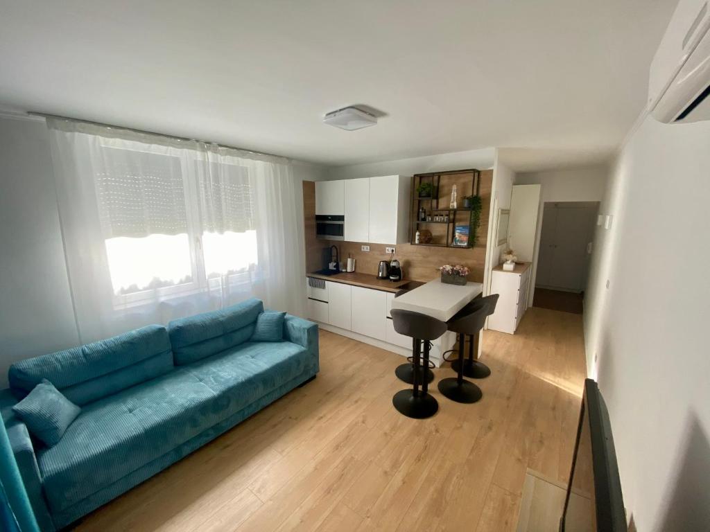 a living room with a blue couch and a table at PannaRoza Apartman in Balatonlelle