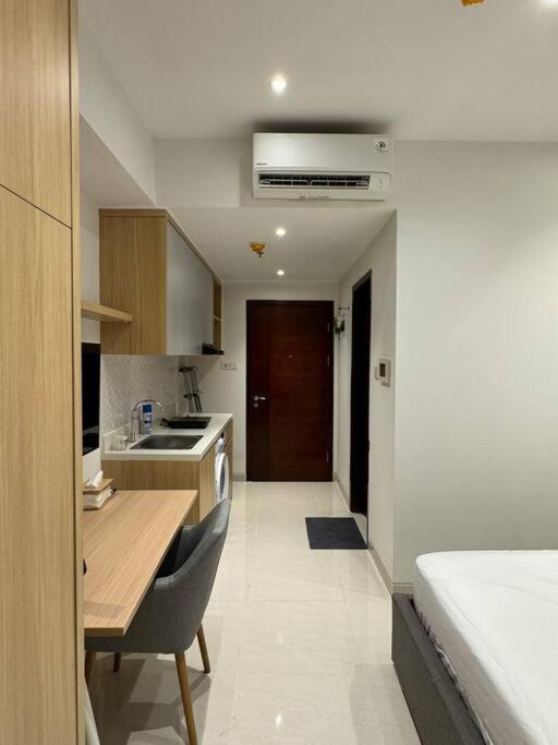a kitchen with a wooden table and a kitchen with a sink at West Vista Studio Apartment with Netflix in Jakarta