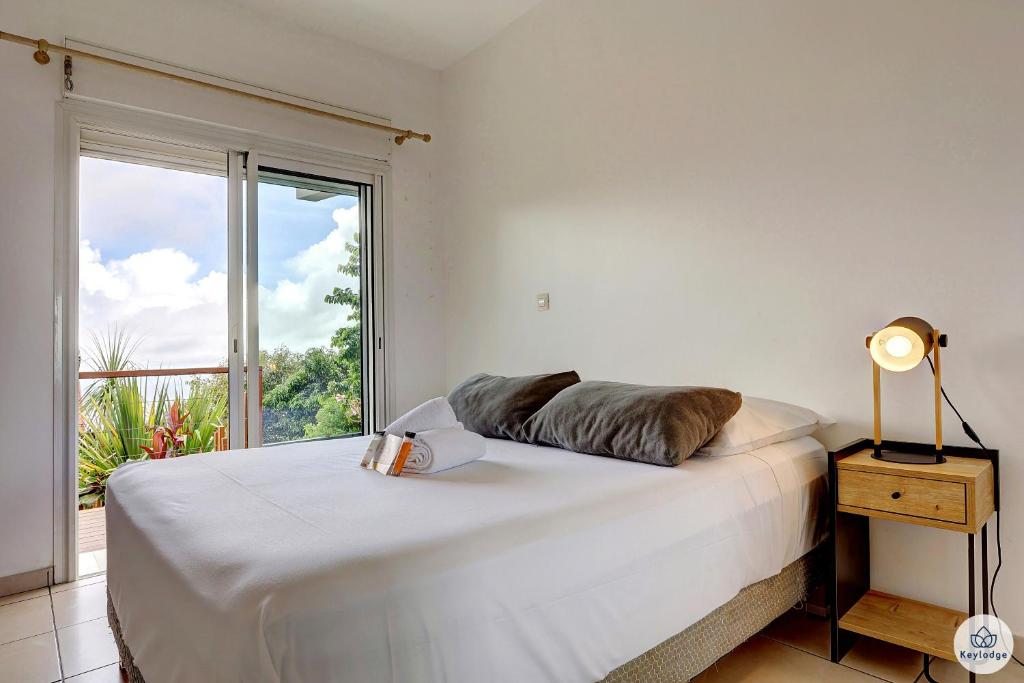 a bedroom with a bed with a large window at Ti Kaz Bellevue - villa avec vue mer - jacuzzi - Saint-Denis in Saint-Denis