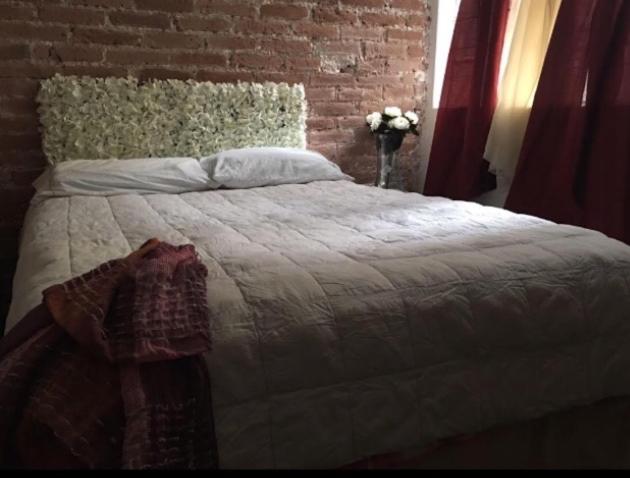 een slaapkamer met een groot bed met een bakstenen muur bij Cómoda y linda habitación cerca del WTC in Mexico-Stad