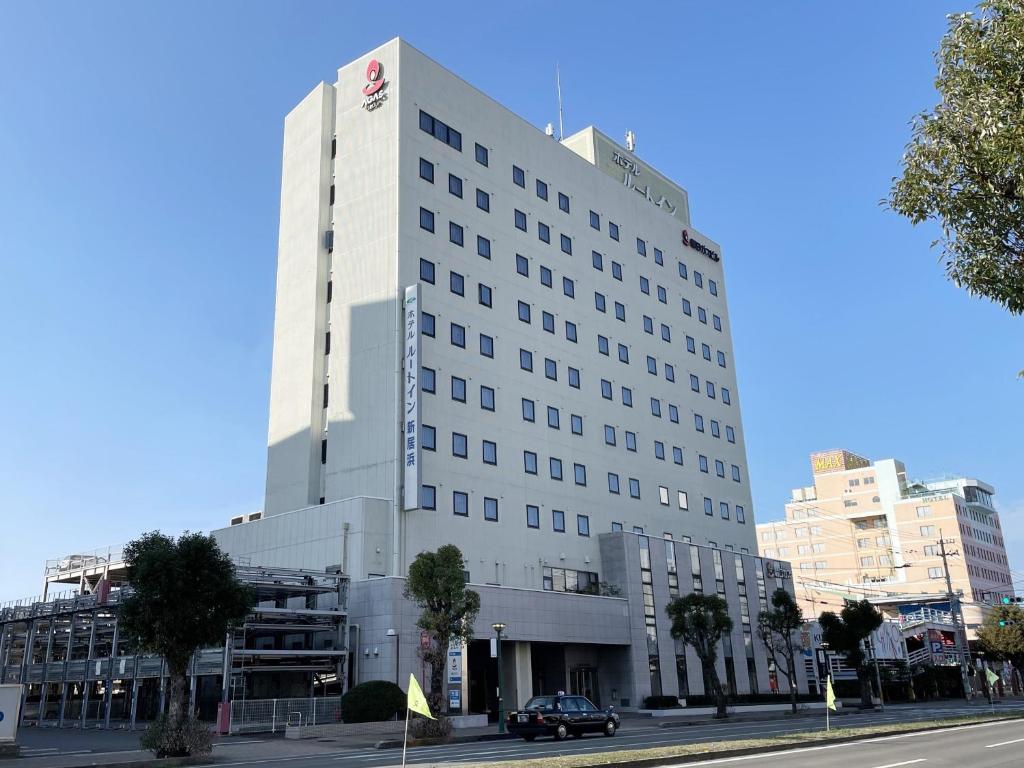 a large white building on a city street at Hotel Route-Inn Niihama in Niihama