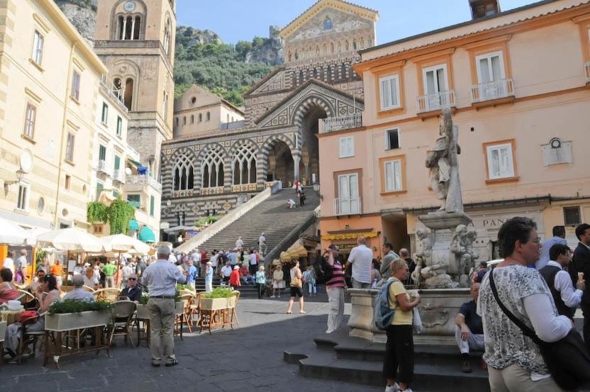 a group of people standing around a fountain in a city at La Piazzetta in Amalfi