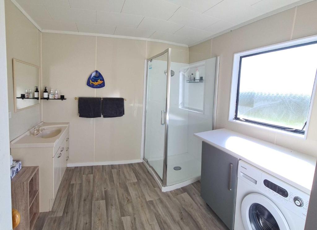 y baño con ducha y lavadora. en Wharewaka Haven, en Taupo