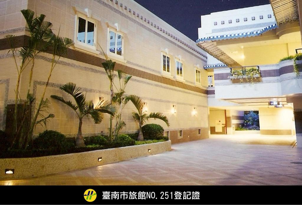 台南的住宿－御宿Motel-台南館，一座大建筑,庭院里种有棕榈树