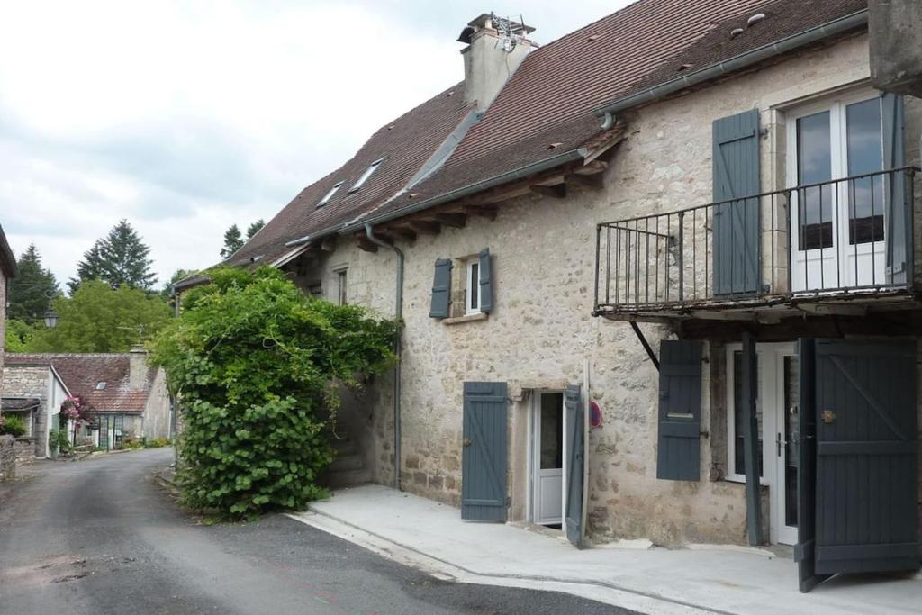 ein altes Steinhaus mit grünen Türen auf einer Straße in der Unterkunft Maison de village rénovée in Meyronne