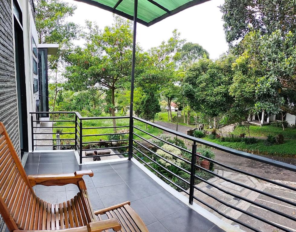 un porche con banco y sombrilla en Villa Omahe Dewe by Da- hee, en Bandungan