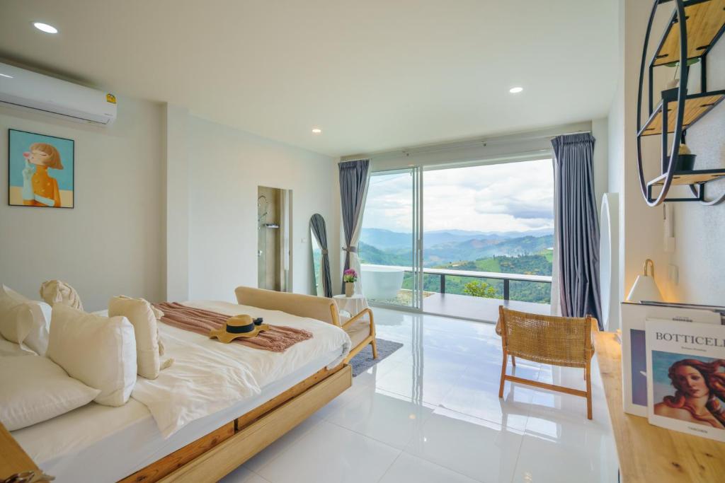 a bedroom with a bed and a large window at Phu Phop Kham in Ban Huai Khai