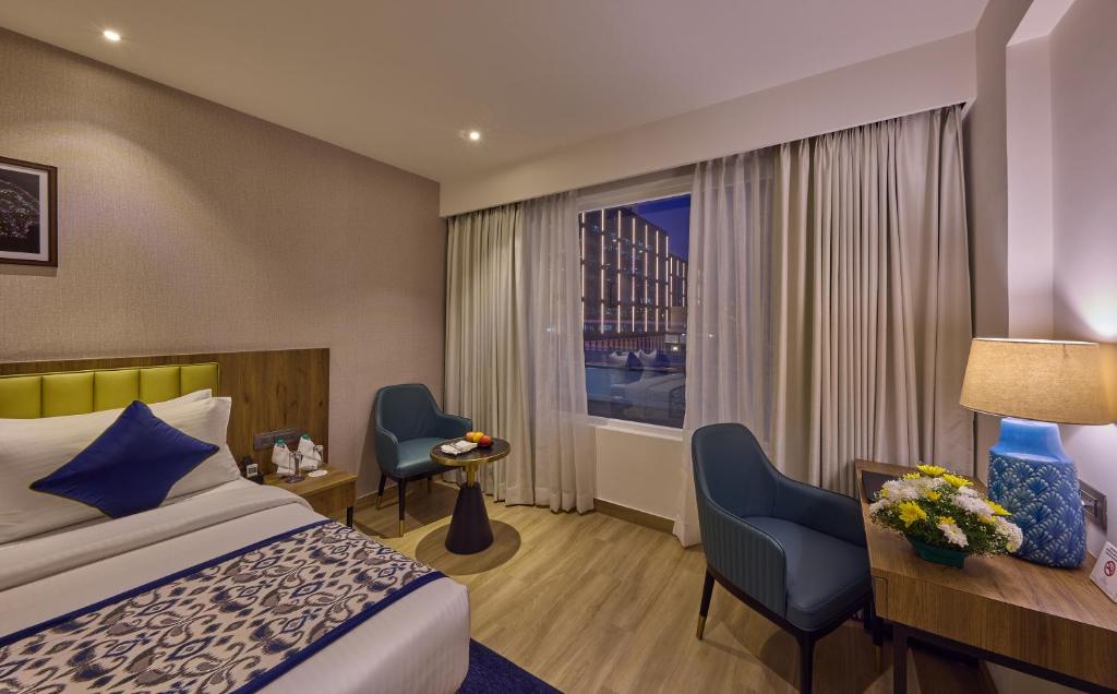 um quarto de hotel com uma cama e uma janela em Grand Continent Hebbal A Sarovar Portico Affiliate Hotel em Bangalore