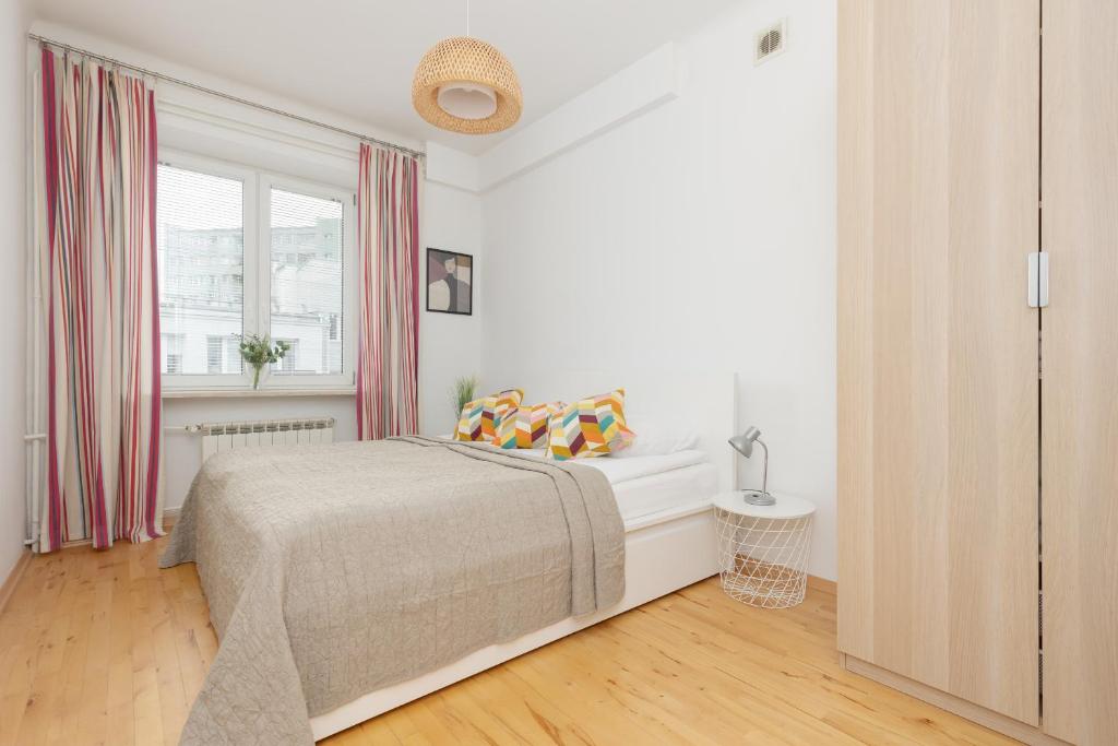 a white bedroom with a bed and a window at One-Bedroom Capital Apartment by Renters in Warsaw