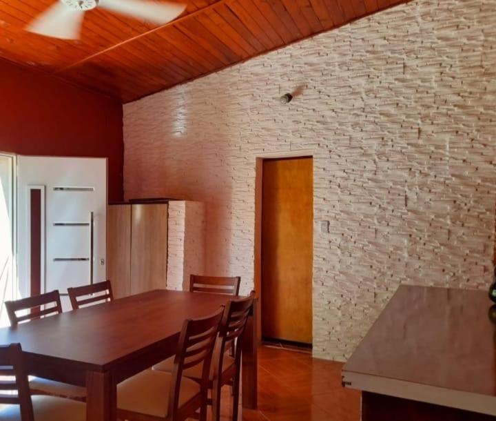 a dining room with a table and chairs and a brick wall at Los Velitos in Santa Rosa del Conlara