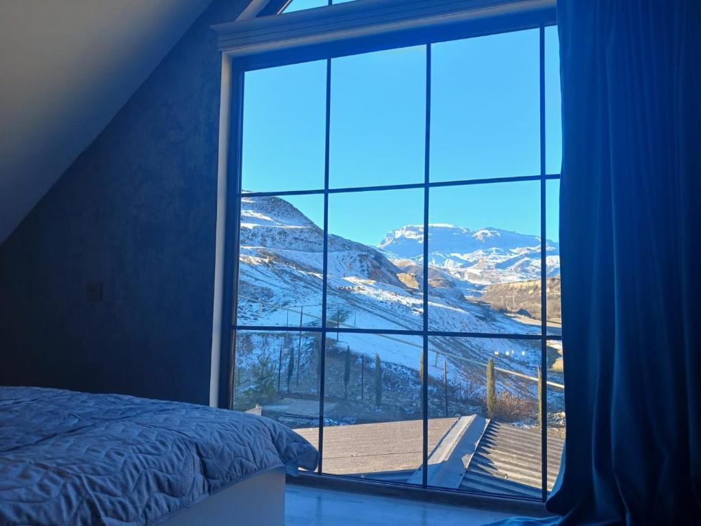 a bedroom window with a view of a snowy mountain at Shahdag Mountain House in Qusar