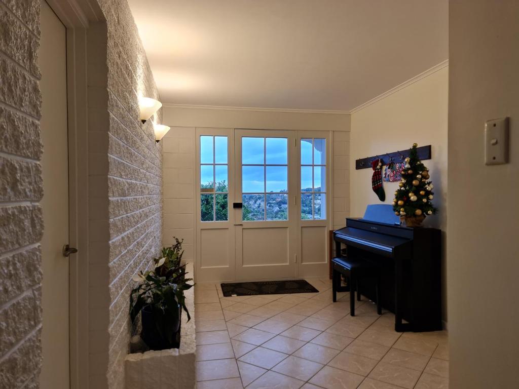 a hallway with a piano and a door with windows at Hillcrest Villa in Auckland
