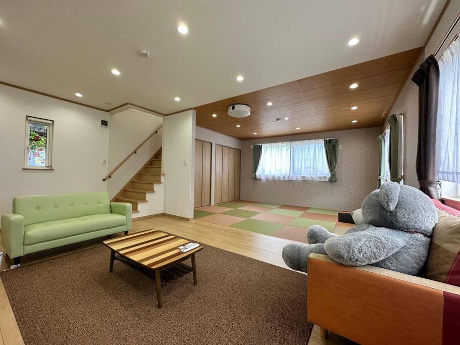 Shirahama Yamate Rent Villa A-2-3 في شيراهاما: غرفة معيشة مع دمية دب كبيرة على أريكة