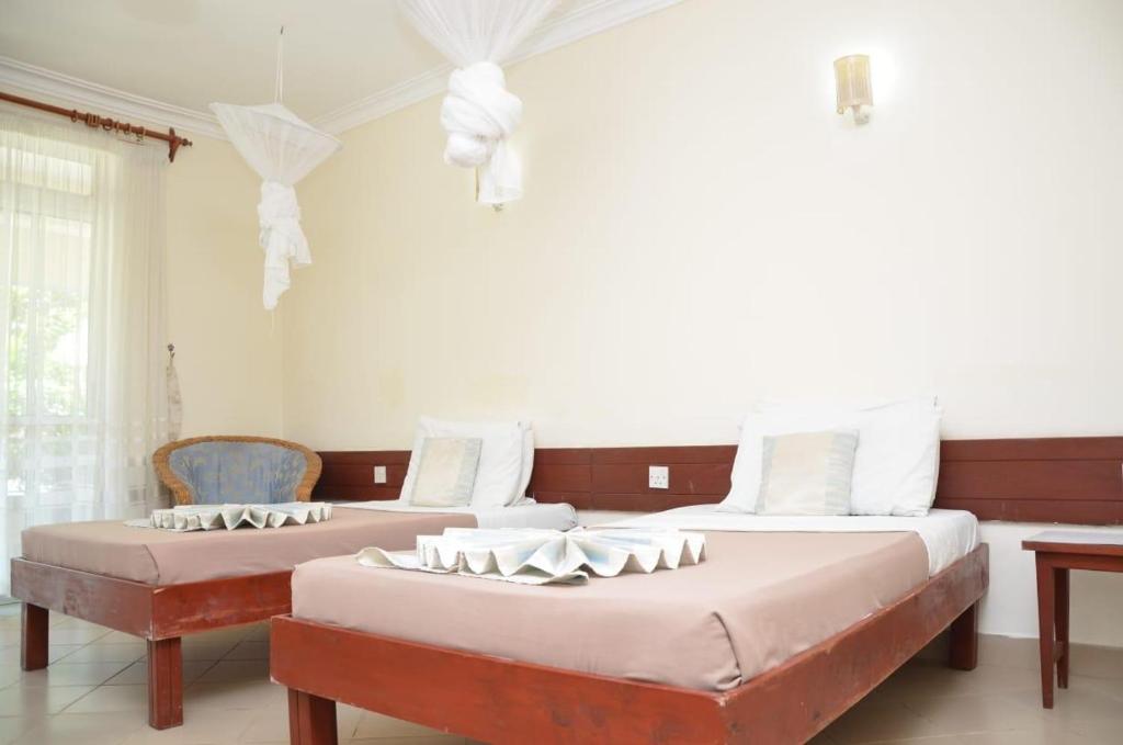 2 Betten in einem Zimmer mit weißen Wänden in der Unterkunft ASINS HOLIDAY INN HOTEL in Ukunda