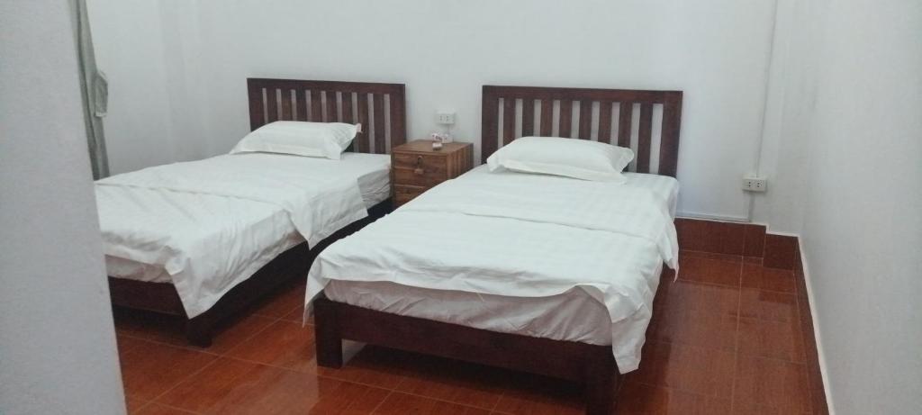 2 camas en una habitación con sábanas blancas en 阳光客栈 en Luang Prabang