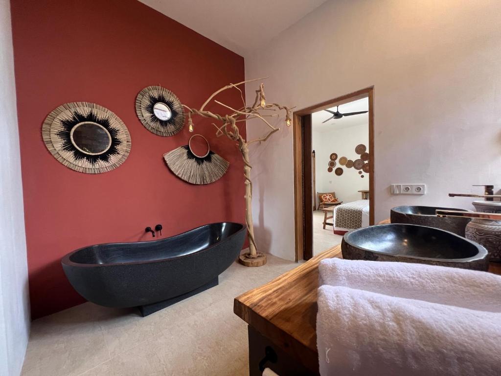 龍目島的住宿－Lasai Villas，浴室设有两个黑色浴缸,拥有红色的墙壁