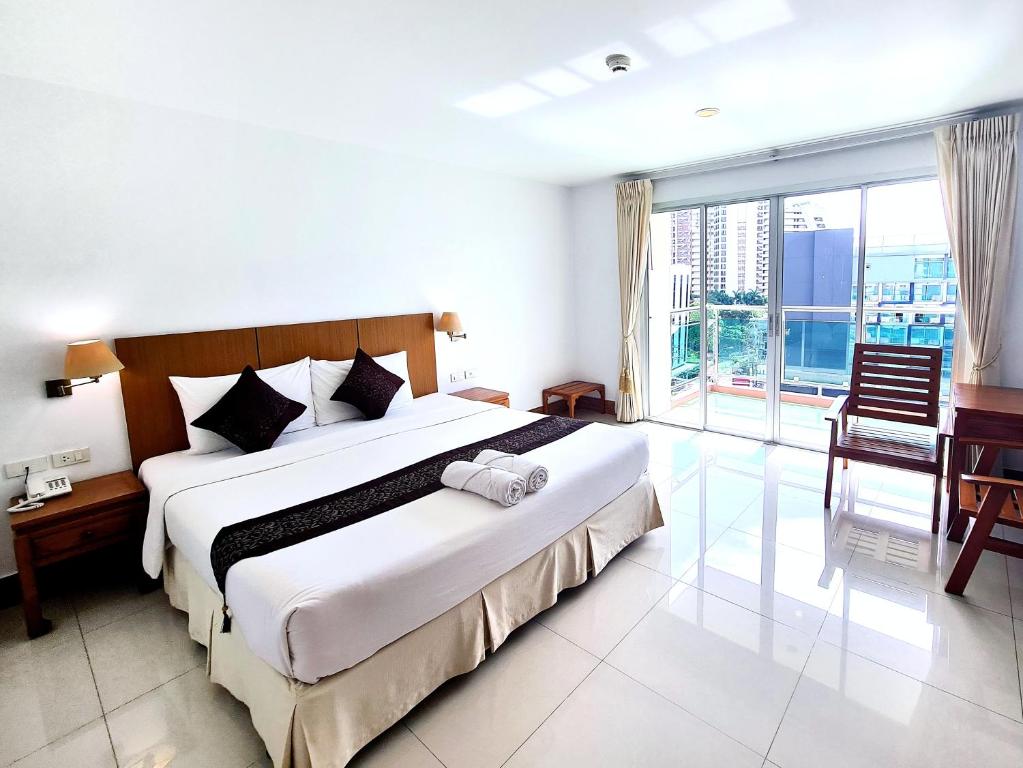 um quarto com uma cama grande e uma janela grande em Nanthana Villa em North Pattaya