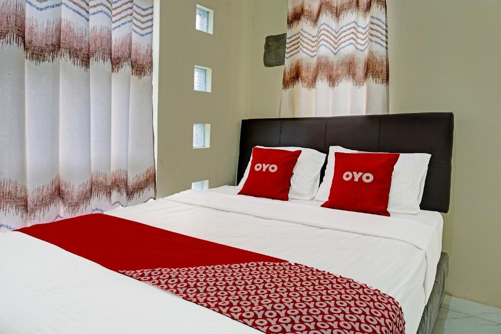 a bedroom with a large bed with red pillows at OYO 91707 Jannah Homestay Syariah in Dau