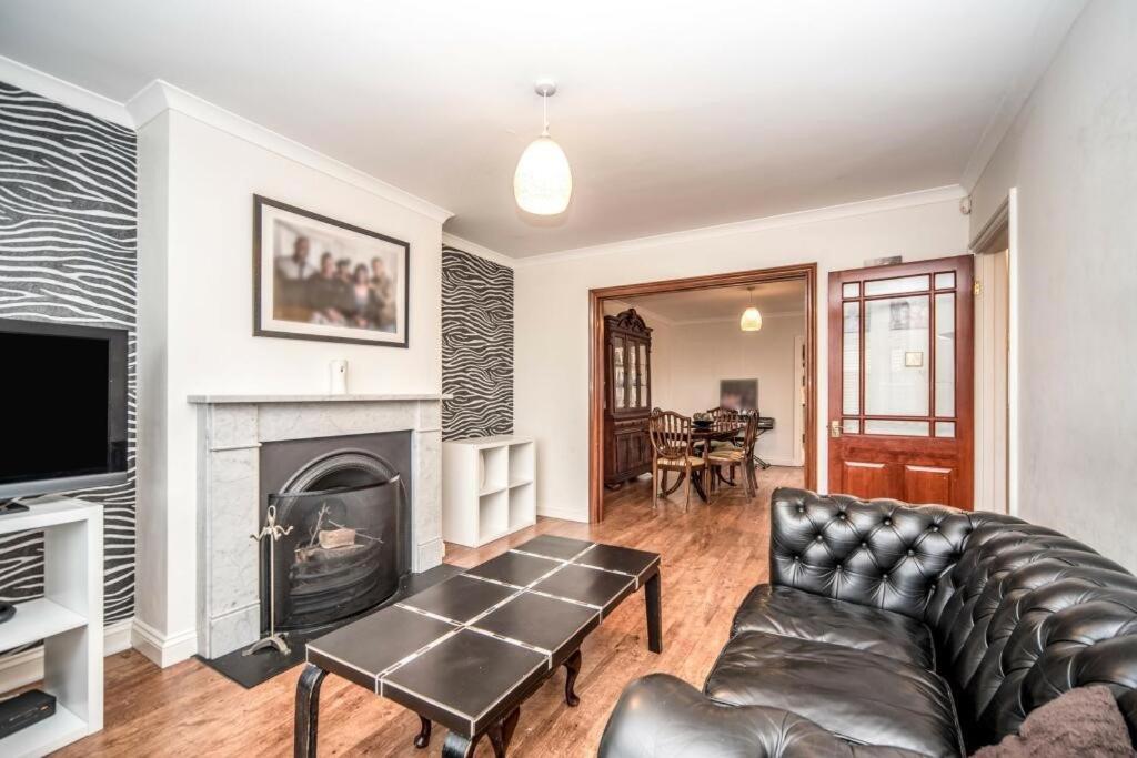 a living room with a leather couch and a fireplace at 3 mins from the theme park! Charming Bedford Hideaway! in Kempston