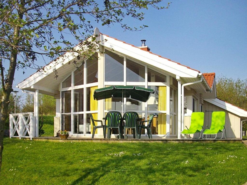 eine abgeschirmte Veranda eines Hauses mit grünen Stühlen in der Unterkunft Three-Bedroom Holiday home in Otterndorf 13 in Otterndorf