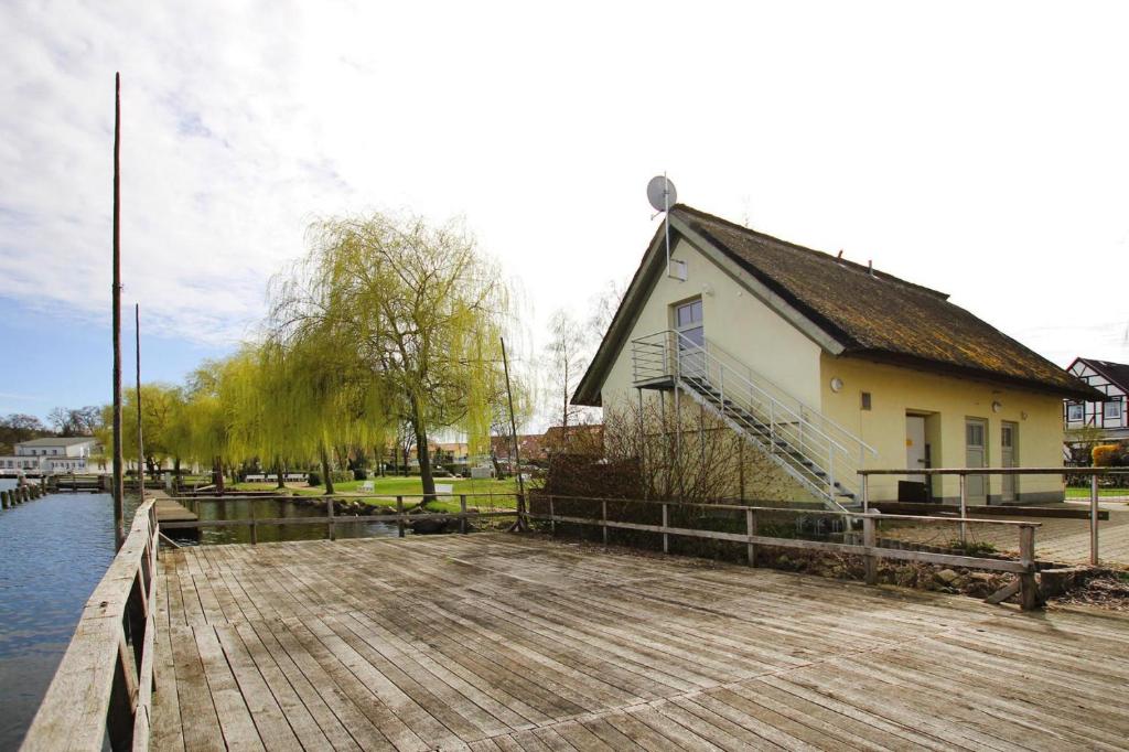 a building on a dock next to a house at Holiday flat am Krakower See Krakow am See - DMS02203-P in Krakow am See