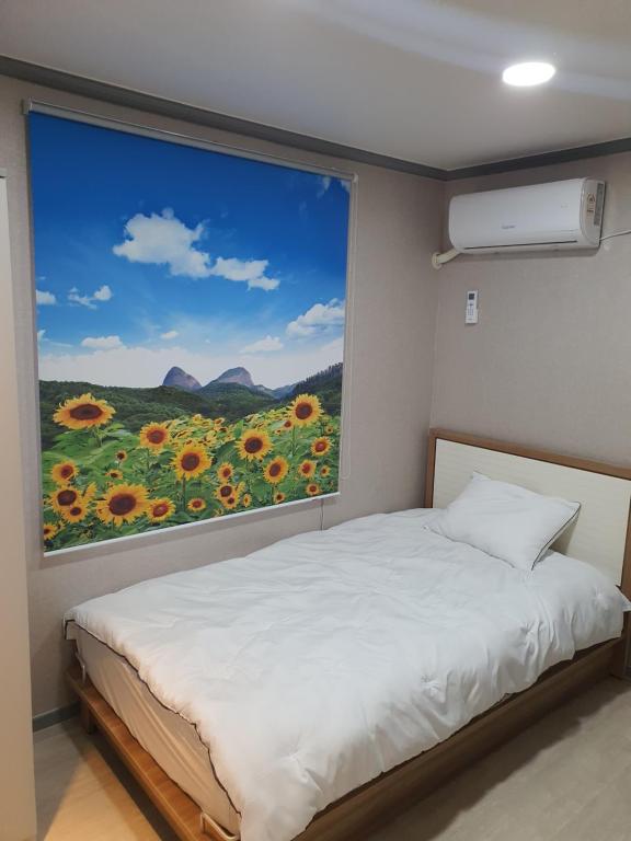 a bedroom with a window with a view of a field of sunflowers at Ara Guesthouse in Busan