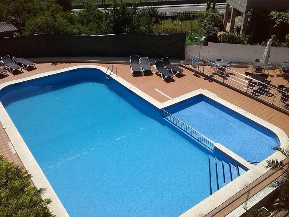 uma grande piscina azul com algumas cadeiras em Hotel Las Vegas em Cangas de Morrazo