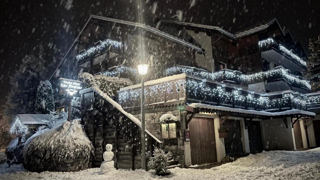 ein schneebedecktes Haus vor einem Gebäude in der Unterkunft Chalet Hôtel Les Airelles in Pralognan-la-Vanoise