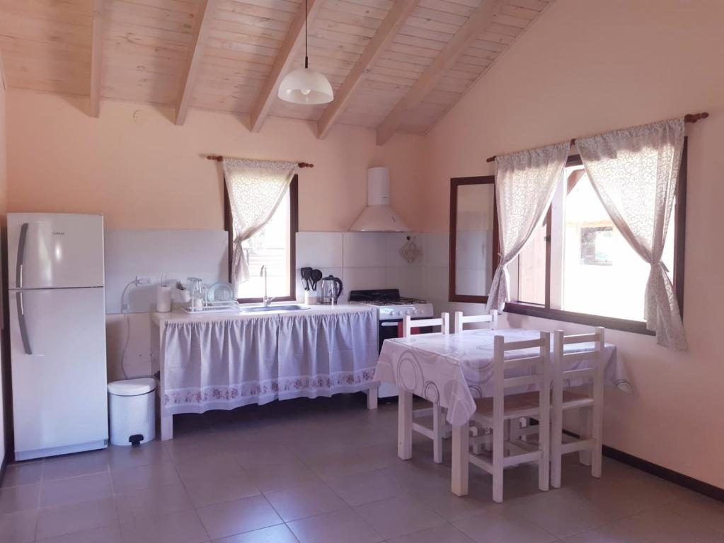 a kitchen with a table and a refrigerator at Cabañas Alma del Sur in El Hoyo