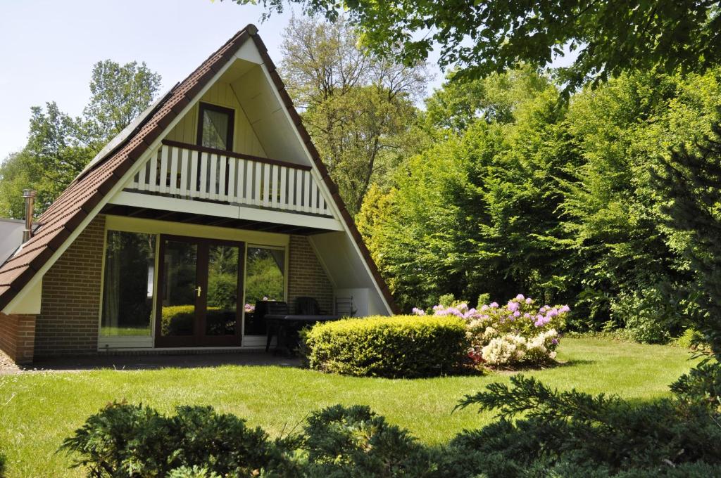 una pequeña casa con jardín y flores en Summio Bungalowpark Het Hart van Drenthe, en Zwiggelte