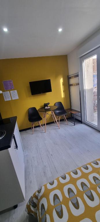 a room with a table and two chairs and a tv at Studio Jasmin tout confort, rénové in Saint-Quentin