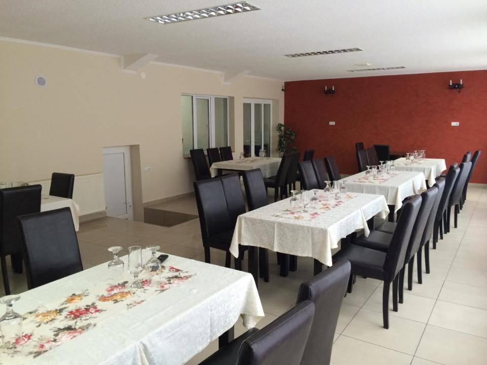 a dining room with white tables and black chairs at Pensiunea Valea Frumoasei in Şugag