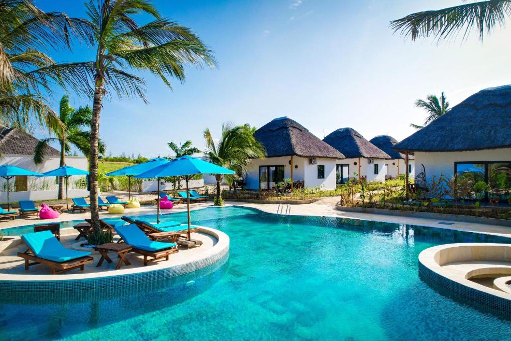 a resort swimming pool with chairs and umbrellas at Turkuaz Beach Zanzibar in Kumba Urembo