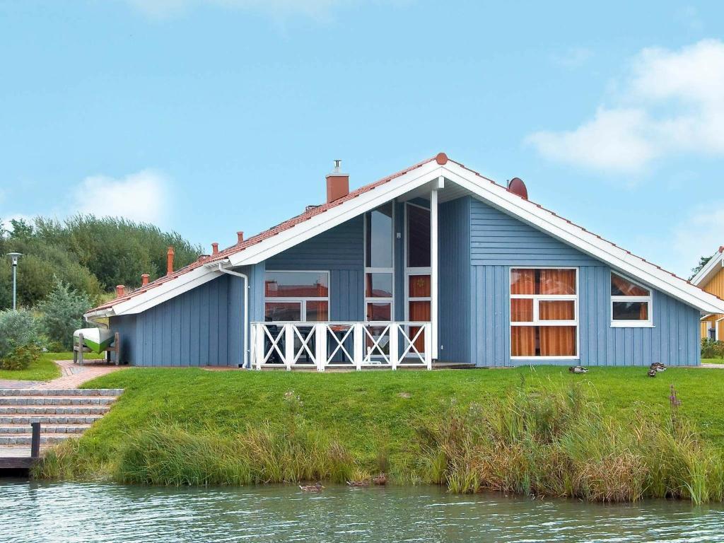 ein blaues Haus neben einem Wasserkörper in der Unterkunft Four-Bedroom Holiday home in Otterndorf 12 in Otterndorf