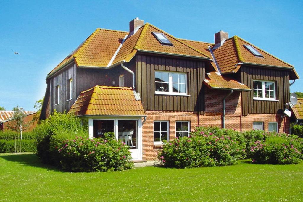 a house with a wooden roof on a green yard at Holiday complex Wenkendorf, Fehmarn-Wenkendorf in Lemkendorf