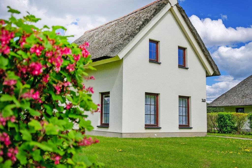 Casa blanca con ventanas rojas y flores rosas en Holiday Resort Van der Valk, Linstow, en Linstow