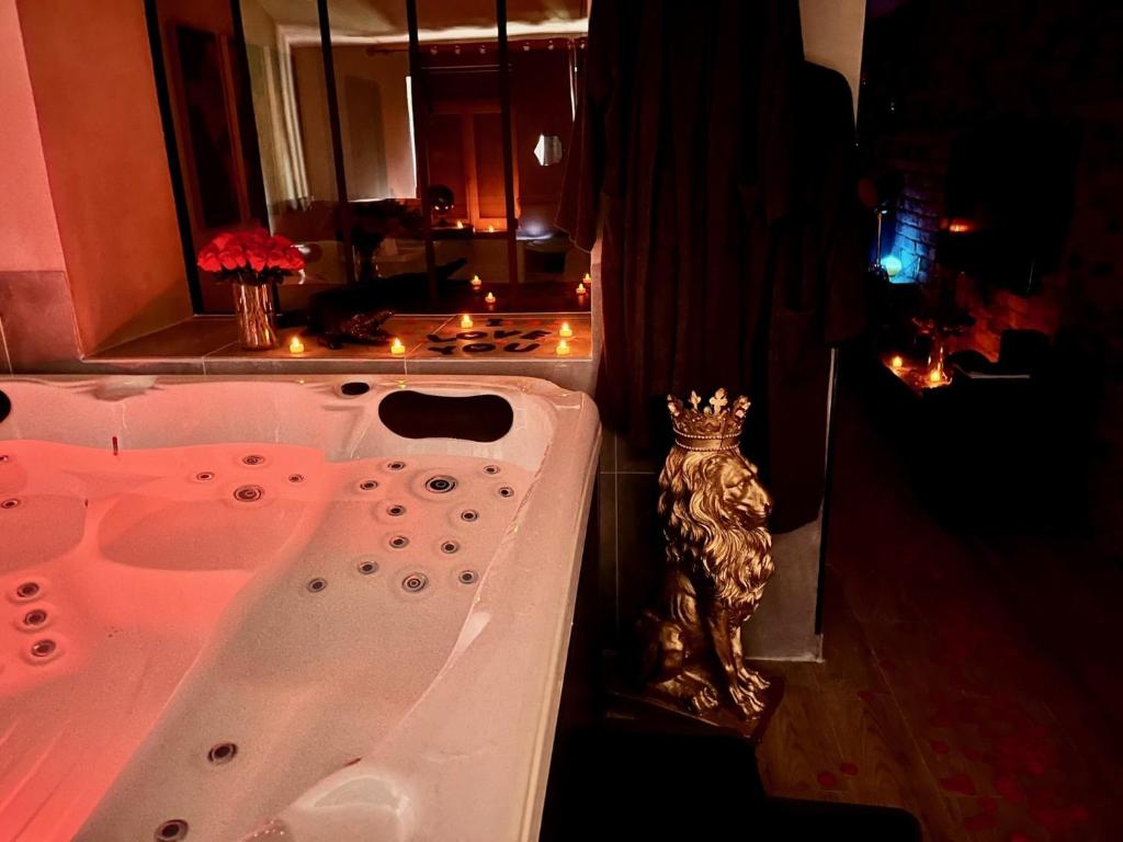 uma casa de banho com uma banheira com uma estátua de um leão em Just'un Instant em Landrecies