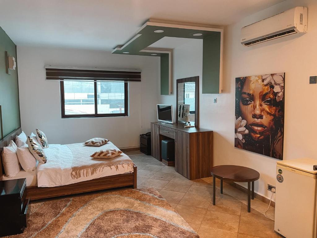 a bedroom with a bed and a desk and a television at Sky Suites-Byblos Hotel Osu in Accra