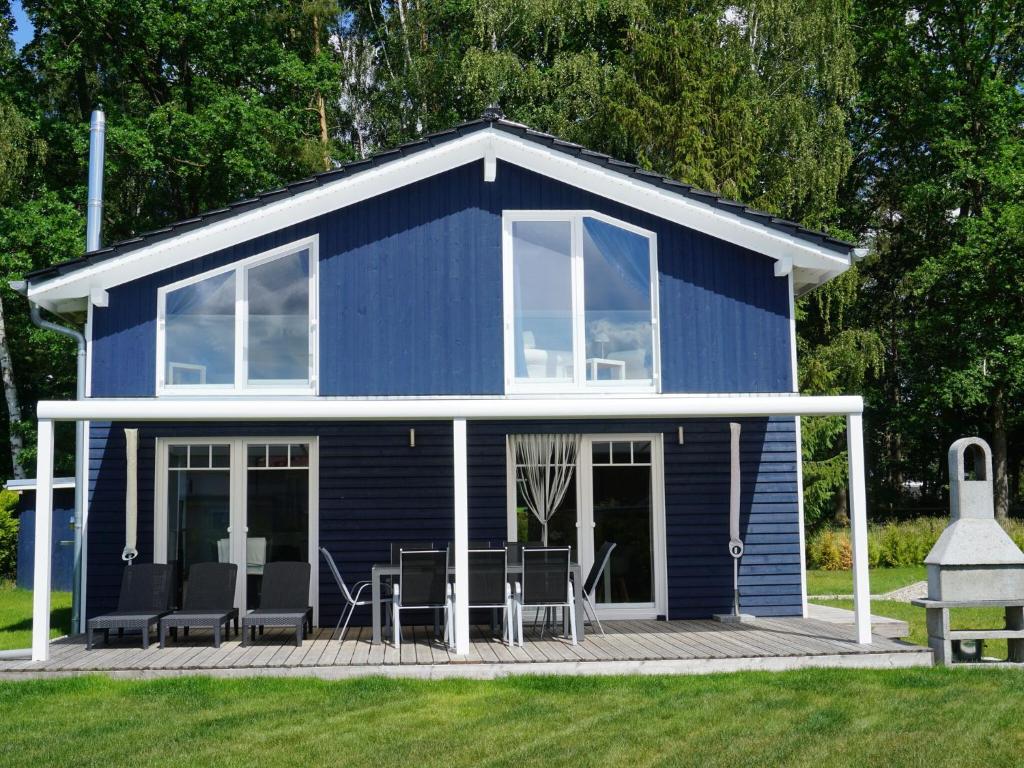 a blue tiny house with chairs on a deck at Ferienhaus Seewind mit Sauna am Dümmer See, Dümmer in Dümmer