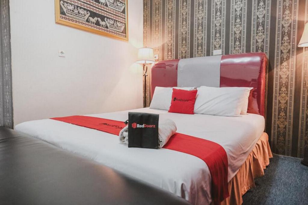 a hotel room with two beds with red and white pillows at RedDoorz Plus @ Jalan Raden Intan Lampung in Bandar Lampung