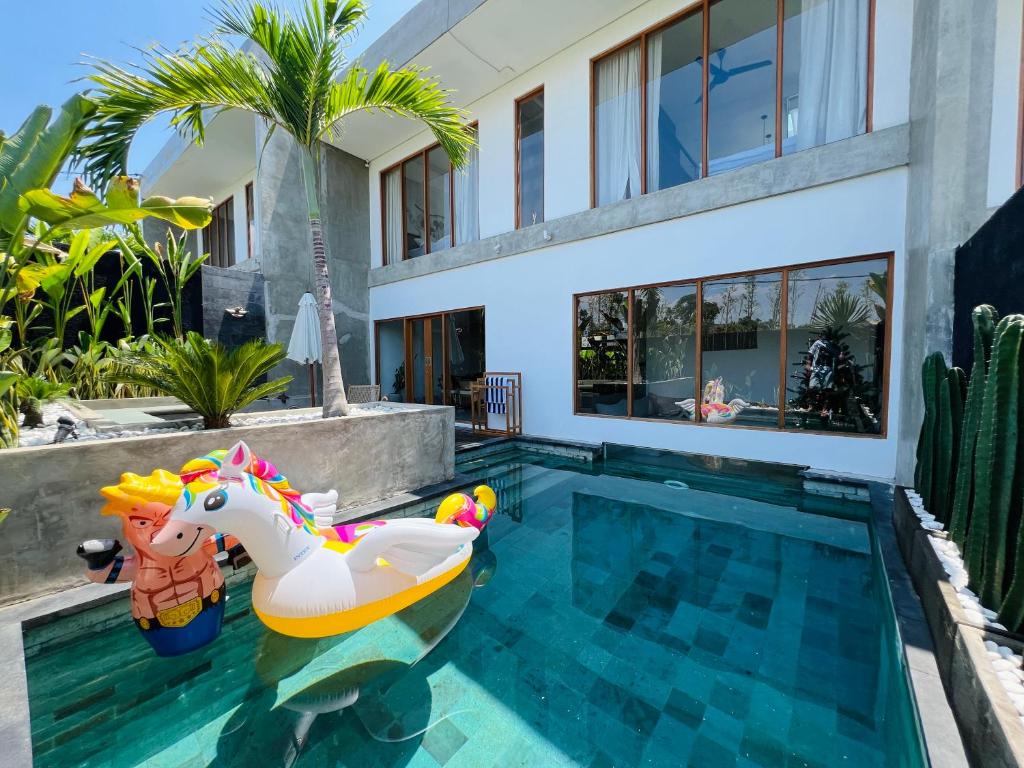 een huis met een zwembad met een opblaasbaar speeltje voor eenhoorns bij Villa Octo 4 - Rice field view and private pool in Canggu