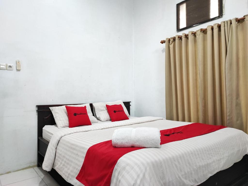 2 Betten in einem Zimmer mit roten Kissen darauf in der Unterkunft RedDoorz Syariah near Universitas Batanghari Jambi in Jambi