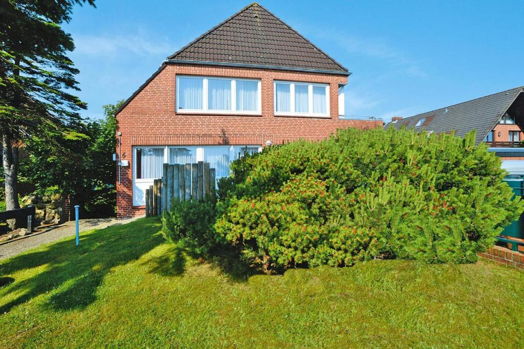 une maison avec un grand bush devant elle dans l'établissement Apartment in Westerland, à Westerland