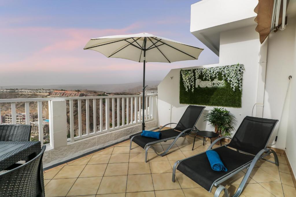 a balcony with two chairs and an umbrella at Bright Amadores Seaview Apartment in Puerto Rico de Gran Canaria