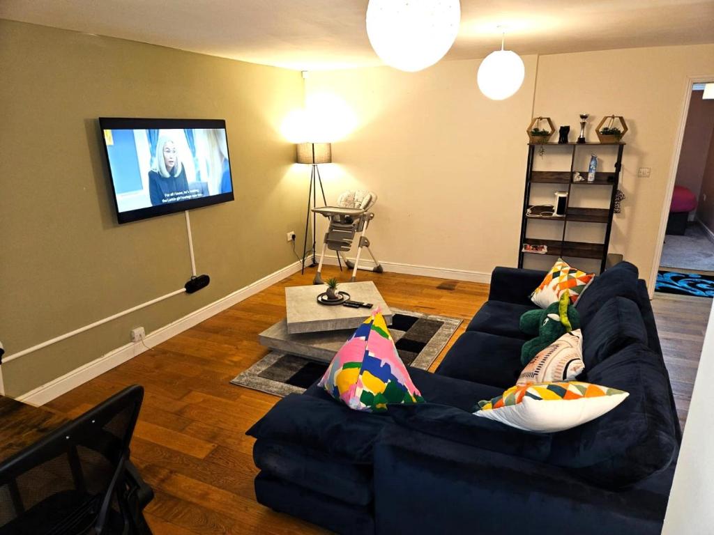 sala de estar con sofá azul y TV de pantalla plana en LONDON FRESHAir BREATHE APARTMENT en Londres